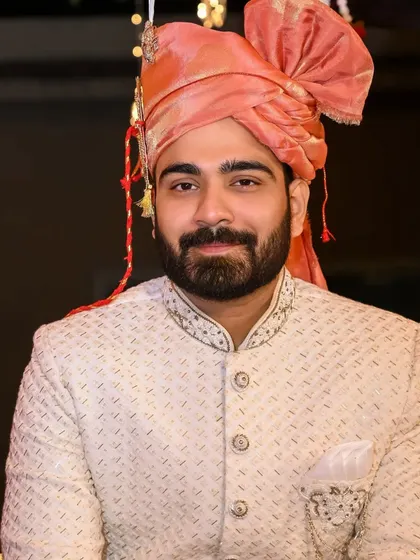 A portrait of a groom in a cream Lakhnavi sherwani. The intricate salli work on the collar and cuffs adds a touch of understated luxury, perfect for a day wedding.
