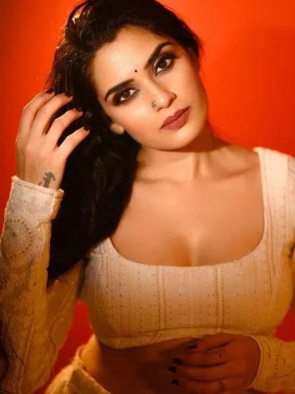 A close-up portrait with a strong, intense expression against a bold red background. The shadows on the face add depth and a cinematic quality to the shot.
