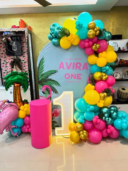 This is a duplicate of ID 41, 103. A vibrant tropical flamingo theme for a first birthday at home. This setup includes a personalized backdrop, a colorful balloon garland, and a flamingo prop.