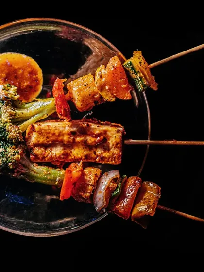 Bon Appétit! A plate of assorted grilled skewers, featuring paneer and colorful vegetables, served with a side of sauce. It's a perfect appetizer, full of smoky flavor.