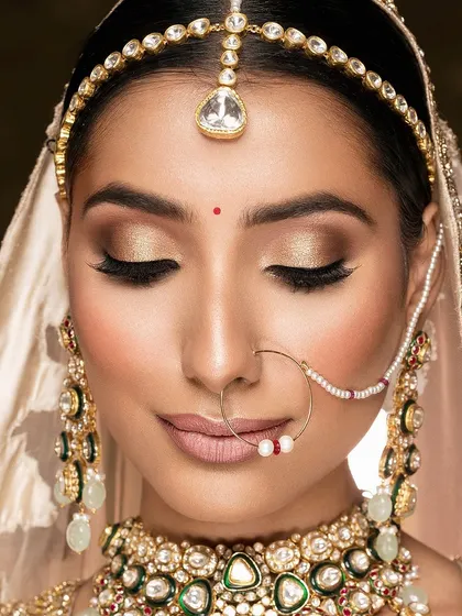 A beautiful shot with eyes closed, focusing on the shimmering gold eyeshadow. This image is all about the makeup artistry and the peaceful, contemplative moment before the wedding ceremonies begin.
