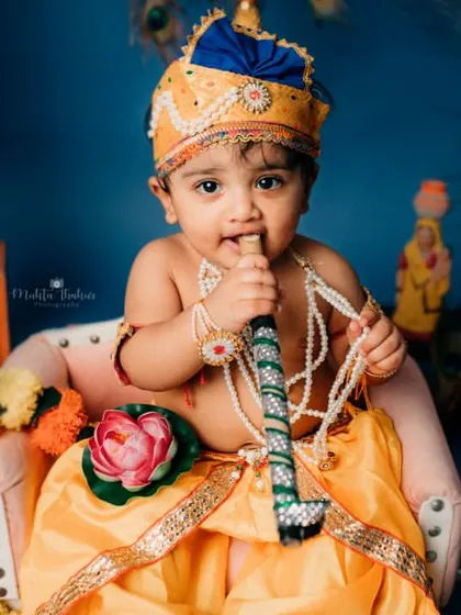 Here, our little Krishna curiously nibbles on his flute. It's these unscripted, natural moments that make for the most memorable baby portraits.