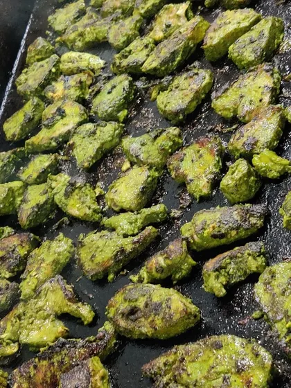 Our hariyali fish tikka grilling on a flat top. The green marinade is made from fresh herbs and spices, giving the fish a vibrant color and a zesty flavor.