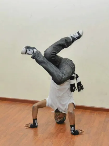 An instructor holding a headstand, a foundational move in b-boying and hip-hop dance styles.