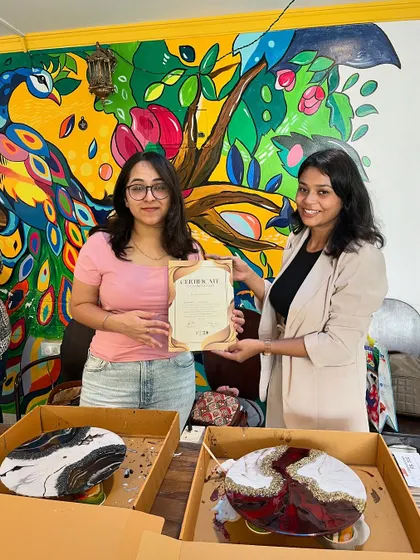 Two participants receive their certificates, showcasing the geode and marble style resin clocks they created.
