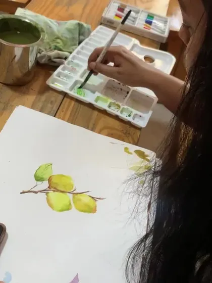 A student works on her lemon painting. Mastering watercolor is a matter of focus, and our classes help you find that creative zone.