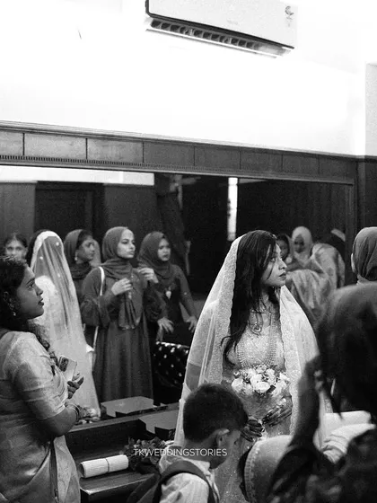 A candid black and white shot of a bride surrounded by the women in her family during the ceremony, capturing a real and unstaged moment.