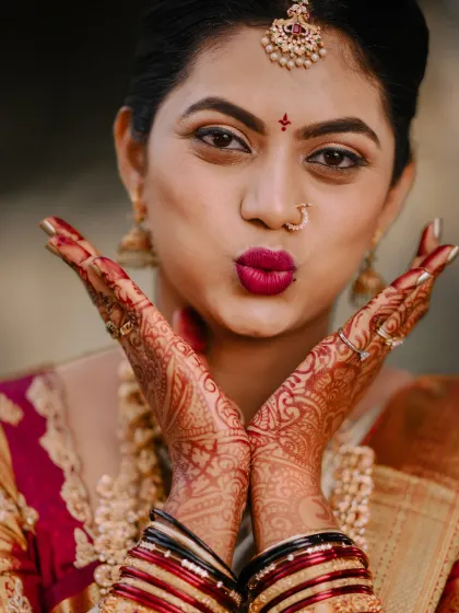 A cute and playful close-up. This highlights her bold lip colour and the intricate details of her mehndi.