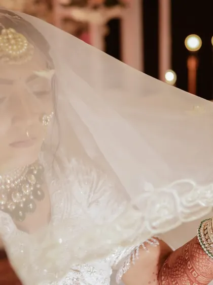 A dreamy, soft-focus shot of the bride through her white veil. This artistic portrait highlights her elegance and the delicate details of her look.