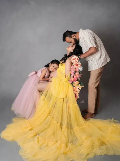 A beautiful family moment filled with love and tenderness. The daughter rests on her mom's bump while her dad gives a sweet kiss, perfectly capturing the anticipation.