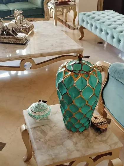 An overhead view of a seating arrangement, highlighting a custom-built turquoise velvet armchair with a gold-finished frame. The shot also shows a matching side table with a marble top, emphasizing our attention to coordinated details.