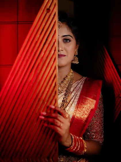 An artistic shot of the bride peeking from behind a red screen, creating a sense of mystery and elegance.