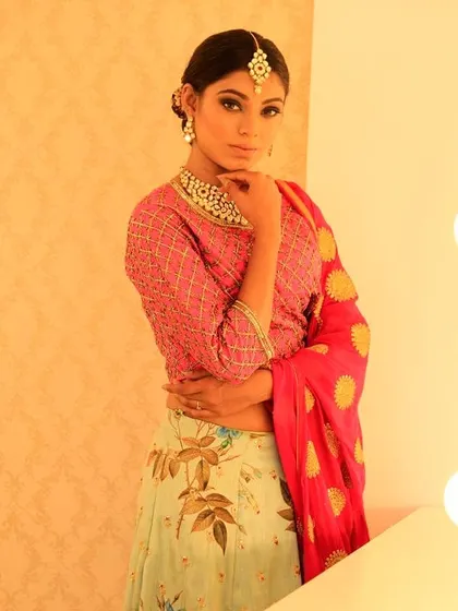 A lovely combination of a pastel floral skirt with a contrasting bright pink embroidered blouse. The look is tied together with a matching pink dupatta with gold motifs, creating a balanced and festive outfit.