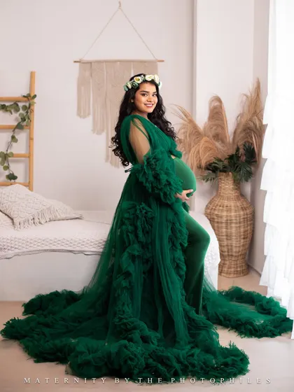 A full-length solo portrait of the mom-to-be in a stunning green gown, looking radiant and confident.