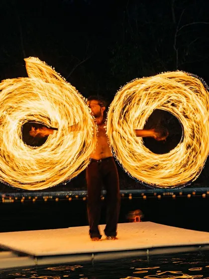 The fire artist creates two perfect circles of flame, demonstrating incredible control and coordination during the evening entertainment.