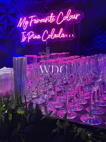 Another fun neon sign, 'My Favourite Colour Is Pina Colada', glowing above the bar, adding a playful and personal touch to the party decor.