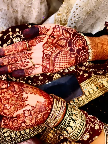 A beautiful candid shot of the rich henna stain, perfectly complementing the bride's ornate wedding outfit and jewelry.