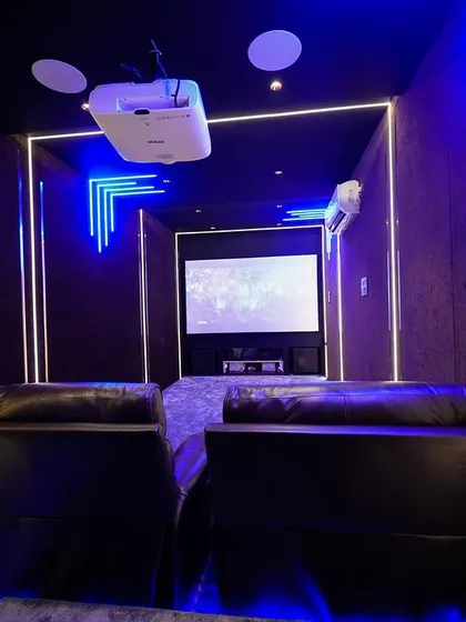 A head-on view of the two main recliners, bathed in the cool blue light of the room's ambient lighting system.