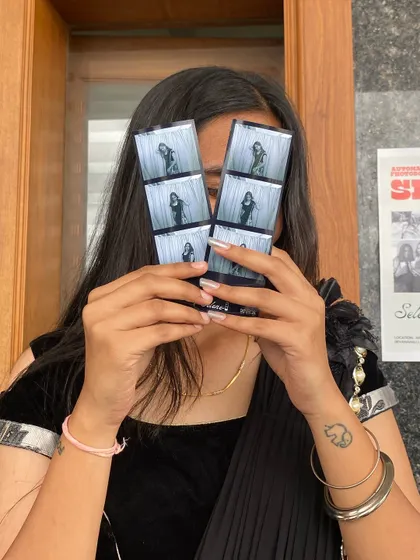 A student playfully hiding behind her new photo strips.