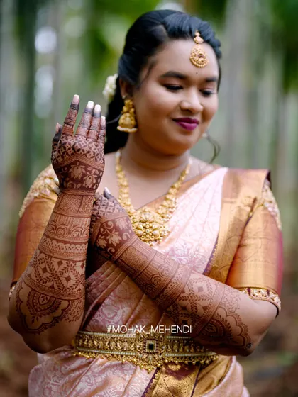A happy bride admiring her mehndi. The rich, dark stain on her hands and arms is the result of using premium, all-natural henna and following the right aftercare process.