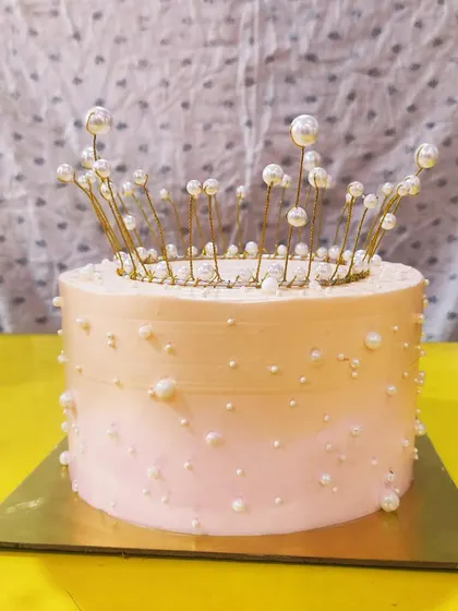 Feel like royalty with this pearl crown cake. The smooth ombre buttercream is adorned with scattered edible pearls, and the cake is topped with a delicate, non-edible wire and pearl crown.