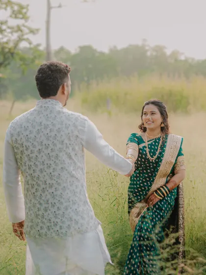 A beautiful shot of the groom leading his bride through a sun-drenched field. This image has a lovely, story-like quality, full of warmth and romance.