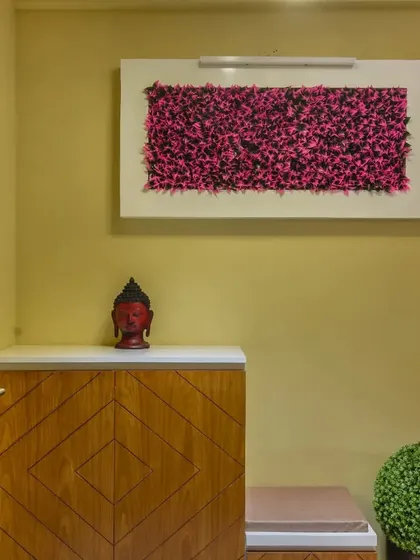 A compact foyer unit with a diamond-patterned wooden shoe cabinet and a small seating stool. The vibrant pink wall art adds a bold splash of color to the entrance.