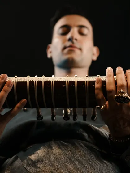 A close-up on my hands and sitar, showing the intricate details of my rings and henna.