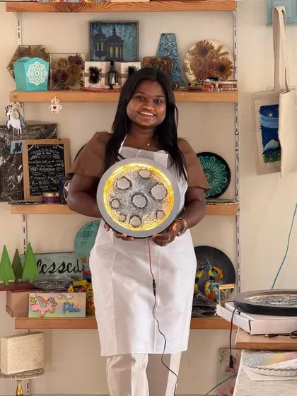 A participant proudly holds up her finished moon lamp in my studio. The detailed craters and glowing light make it a truly special piece to take home.