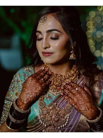 A moment of quiet reflection. This shot captures the intricate details of the bride's makeup and her stunning temple jewellery, showcasing the artistry and craftsmanship involved in creating the perfect bridal look.
