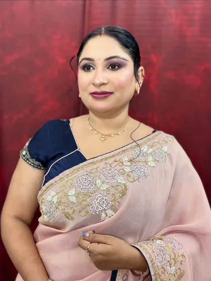 A front-facing view of the soft glam makeup, showing the subtle purple-toned eyeshadow that complements her navy blue blouse.