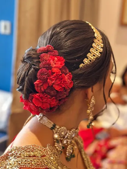 Another angle of the red carnation bridal bun, showing how the flowers are carefully placed to create a full, lush look. The style is both secure and visually striking from every viewpoint.