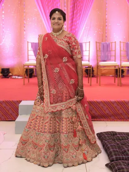 A bride looking gorgeous in a red and peach toned lehenga. The detailed embroidery and flattering silhouette make it a wonderful choice for the wedding day.