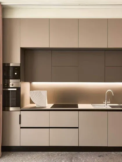 A minimalist kitchen in a warm beige tone. The clean lines and integrated appliances are perfect for someone who loves an uncluttered look. The strip of LED lighting provides beautiful ambient light.