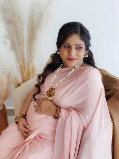 A seated portrait of the mom-to-be, looking radiant. The makeup is designed to catch the light beautifully, with a focus on glowing skin and defined eyes.