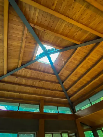 Looking up at the vaulted wooden ceiling with a central skylight. This architectural feature floods the interior with natural light and adds a sense of volume and airiness.