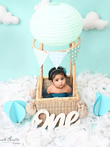Up, up, and away! This sweet baby girl is ready for an adventure in her very own hot air balloon. This whimsical setup is a creative and beautiful way to mark a first birthday.