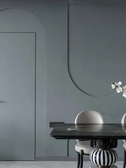 The 'House of Arcs' lives up to its name with curves and arches integrated throughout the design. Here, a flush door is set within a wall featuring decorative arched grooves, creating a subtle yet cohesive design language.