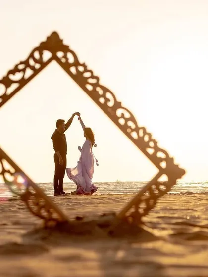 Using a prop like an ornate frame, we can create unique and artistic silhouette shots during a sunset beach session. It adds a creative touch to your couple portraits.