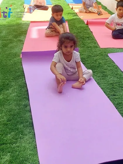 A young child sits quietly on her yoga mat. Yoga also teaches children moments of stillness and calm.