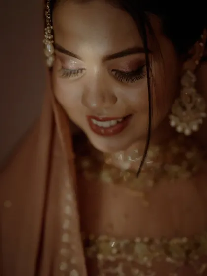 A close-up portrait of the bride, her face illuminated by a soft light that highlights her beautiful smile and makeup.