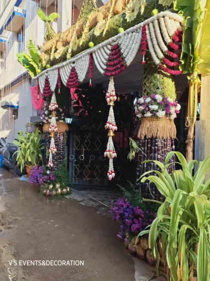 A closer look at the side of the entrance, detailing the sugarcane pillars and the base of purple flowers and painted coconuts.