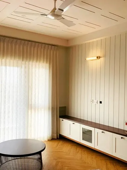 At least this site will need a professional photo shoot. A stunning living room with a paneled ceiling, fluted wall, and herringbone flooring.
