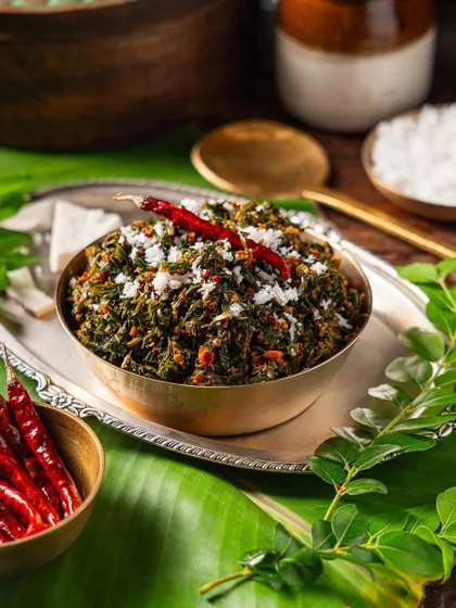 A styled shot of a traditional thoran (stir-fried vegetable dish) for a cloud kitchen. We use authentic props like banana leaves and brass bowls.