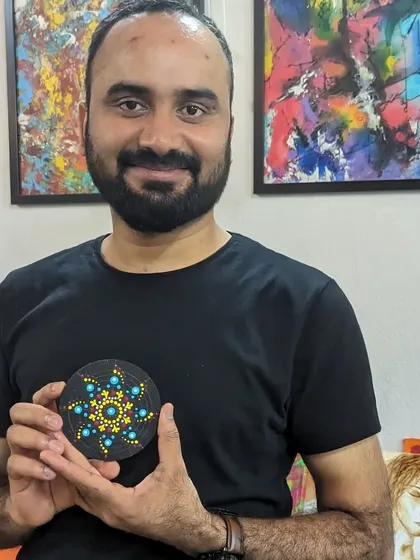 A participant with his finished mini dot mandala coaster, a small but beautiful piece of art.
