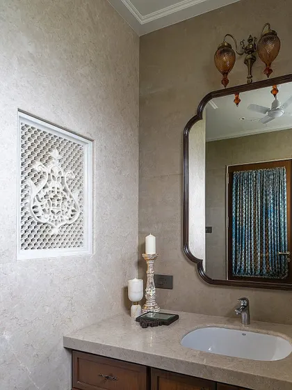 In this Hyderabad bathroom, a handcrafted lattice or 'jaali' panel elegantly divides the shower and dry areas. This element, inspired by traditional Indian architecture, adds a beautiful, handcrafted touch while maintaining a sense of openness.