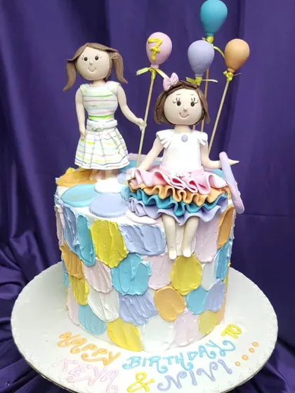 A special custom cake for twin girls. This design features personalized toppers for each girl and a colorful, textured buttercream finish, celebrating their unique bond on their shared birthday.