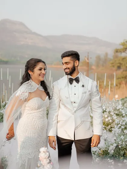 The couple shares a loving glance as they stand at the altar. Their happy smiles and the beautiful lakeside setting make this a perfect portrait of their white wedding ceremony.