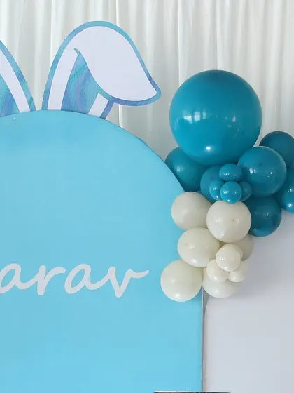 A detail of the bunny-themed backdrop for Aarav's party, showing the bunny ear silhouette and a small balloon cluster.