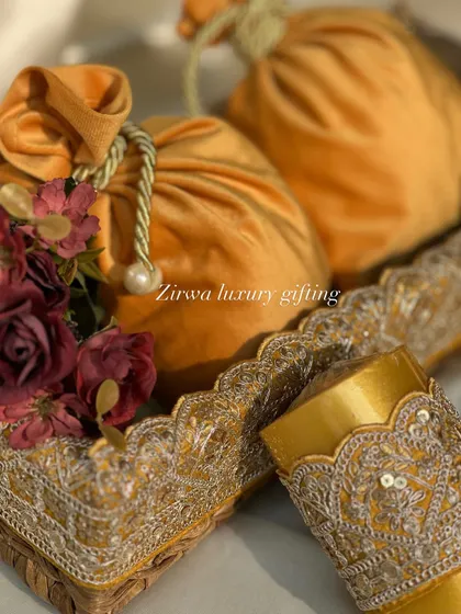 A closer look at the yellow-themed Lohri favours. The rich velvet potlis are complemented by delicate floral arrangements, creating a luxurious and elegant gift.
